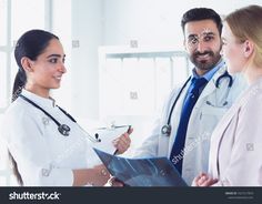 two doctors are talking to each other in the hospital, and one is holding a clipboard