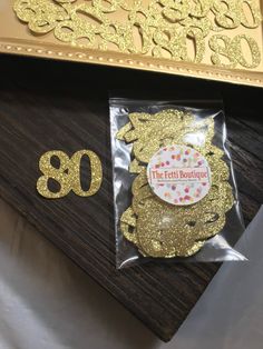 the number 80 is decorated with gold foil and confetti sprinkles