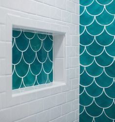 a bathroom with white tiles and green mermaid scales on the wall