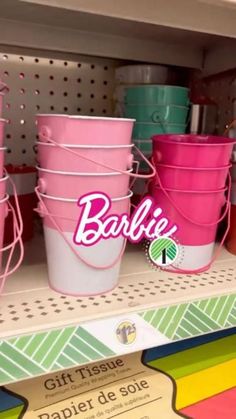 many different colored buckets are on display in a store or office area, with the word barbie above them