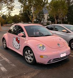 a pink car with hello kitty painted on it's side in a parking lot