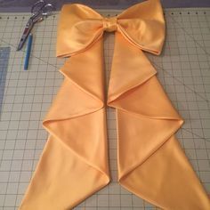 an orange bow sitting on top of a cutting board next to scissors and paper cutters