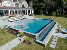 an aerial view of a pool surrounded by lawn chairs and steps in front of a large house