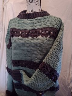 a green sweater with brown and blue stripes on the back, sitting on a mannequin's head