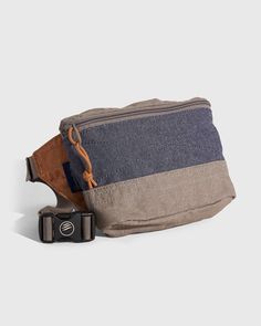 a brown and blue fanny bag sitting on top of a white table next to a black camera