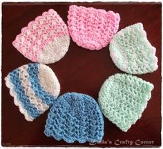 six crocheted hats are arranged on a table