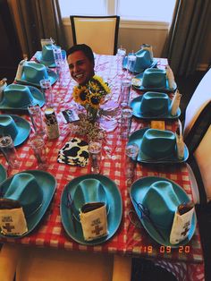 a man sitting at a table with plates and cups on it, smiling for the camera