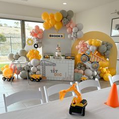 a birthday party with balloons and construction vehicles on the table in front of an entrance