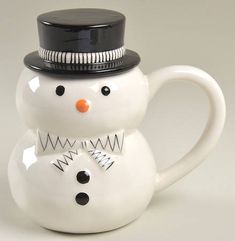 a ceramic snowman mug with a black top hat