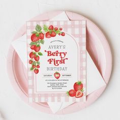 a strawberry first birthday party card on a pink plate