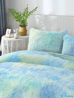 a bed covered in blue and green fluffy blankets