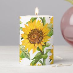 a yellow sunflower candle sitting on top of a table