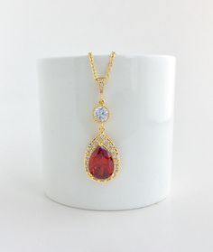 Luxury red ruby cubic zirconia bridal tear drop dangle pendant and necklace in gold plated brass setting. Necklace pendant features a large teardrop with pear cut red ruby cubic zirconia center surrounded by tiny round zirconia crystals and dangles from round cubic zirconia connector and bail. Length of the gold plated chain is 18 inches and comes with 2 inches extender and lobster clasp. For matching earrings click: https://www.etsy.com/listing/667776478/red-crystal-gold-earrings-red-bridal?ref Red Pear-shaped Necklace For Gift, Ruby Teardrop Pendant Necklace, Elegant Red Pendant Bridal Necklace, Ruby Teardrop Pendant Jewelry For Wedding, Ruby Teardrop Necklace For Wedding, Ruby Teardrop Pendant For Wedding, Wedding Ruby Teardrop Pendant Jewelry, Red Teardrop Necklace For Wedding, Gold Cubic Zirconia Teardrop Bridal Necklace