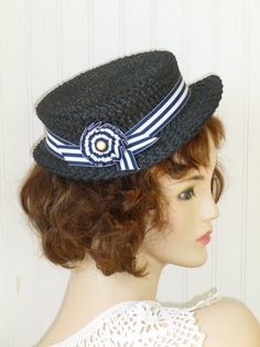 "On the shelf and ready to ship: The is a True Vintage 1940's,   One of a Kind, straw, black,  boater, derby, which has been re-imagined and re-draped. In excellent vintage condition. With a slight wave in the front, the straw layer is doubled for a truly unique look. A navy and white grosgrain ribbon was added around the circumference, then styled into a fan with a true vintage navy and white button center. Best fits size 21.5\" However, it works beautifully as a pillbox, derby for 21\" up to 22.5\", with use of the comb and perhaps a hat pin." Straw Boater, Pillbox Hat, Hat Pin, Pill Boxes, Hat Pins, On The Shelf, Grosgrain Ribbon, True Vintage, A Fan