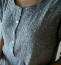 a woman is wearing a gray dress with white flowers on the chest and buttons at the waist