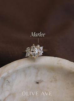 an engagement ring with three stones on top and the words marbee above it in white lettering