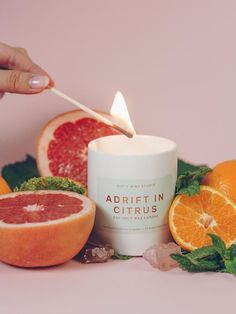 someone lighting a candle surrounded by citrus fruits