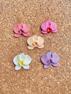 four pairs of flower shaped earrings sitting on top of a cork board floor next to each other