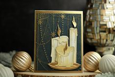 a card with a lit candle on it and some ornaments around the table behind it