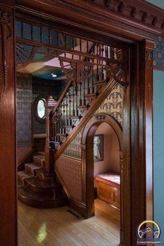 an ornate wooden staircase in a house with blue walls and wood trimming on the stairs