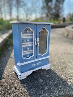 a small blue cabinet sitting on the side of a road