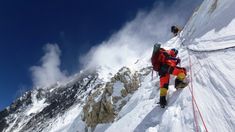 a man climbing up the side of a snow covered mountain