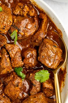 a bowl filled with meat covered in sauce and garnished with cilantro