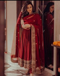 a woman standing in front of a mirror wearing a red dress