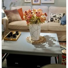 a living room with a couch, coffee table and flowers in a vase on top