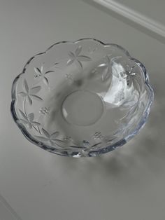 a clear glass bowl sitting on top of a white tablecloth covered floor next to a wall