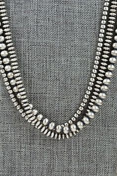 three strands of silver beads on a gray background