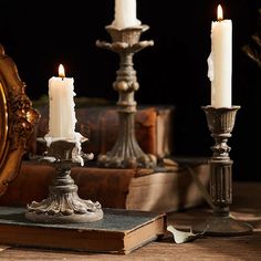 three lit candles sitting on top of a table next to an old book and mirror