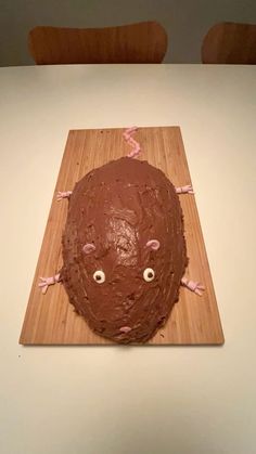 there is a cake that looks like a face on a cutting board with pink ribbon around it