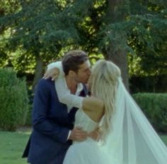 a bride and groom kissing in front of trees