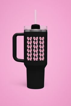 a black coffee cup with pink flowers on the front and sides, sitting against a pink background