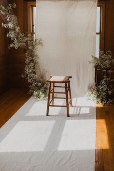 a chair sitting on top of a wooden floor next to a white wall and window