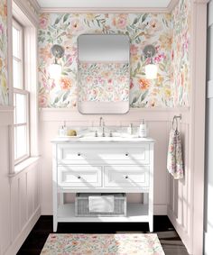 a bathroom with floral wallpaper and pink vanity, gold faucet, mirror and rug