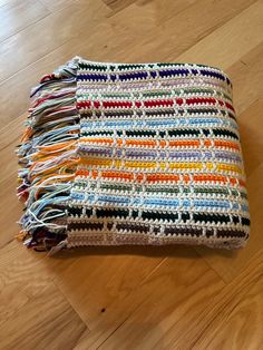 a multicolored crocheted blanket sitting on top of a wooden floor