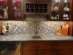 a kitchen counter with wine glasses and bottles on the shelves above it, next to a sink