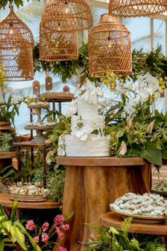 a table topped with lots of cakes covered in flowers and birdscages hanging from the ceiling