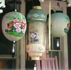 three chinese lanterns hanging from the ceiling in front of a window with flowers on them