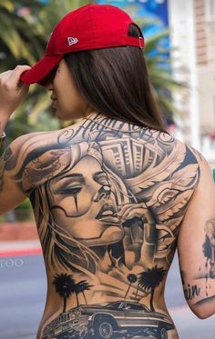 a woman with tattoos on her back is walking down the street while wearing a red hat