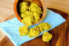 a wooden bowl filled with green food sitting on top of a blue and white napkin