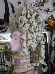 a mannequin head made out of old sheet music notes and ribbons with feathers on it