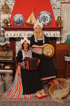 two women dressed in traditional clothing posing for a photo with an accordion and musical instrument