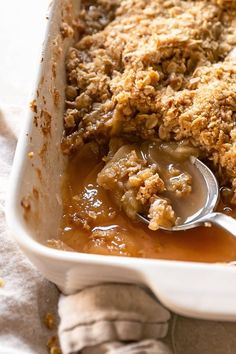 a casserole dish filled with apple crumbles and topped with a spoon