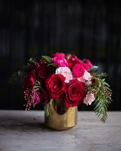 a gold vase filled with red and pink flowers