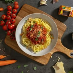 a plate of spaghetti with tomato sauce and parmesan cheese on a cutting board