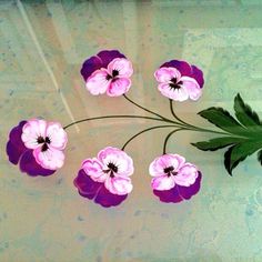 some pink and purple flowers are on a glass table with green leaves in the middle