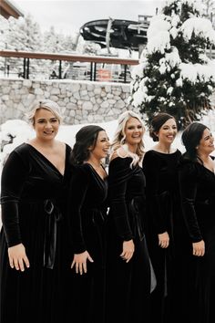 a group of women standing next to each other in front of a snow covered tree